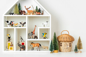 White house shaped shelving with toy animals on white wall. Toys for kids neatly organized on shelves. Interior design. Organizing and Storage Ideas in nursery.
