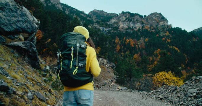 Handheld shot following backpacker tourist on vacation mountain travel at autumn