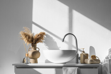 Modern sink, bath accessories and vase with pampas grass near white wall