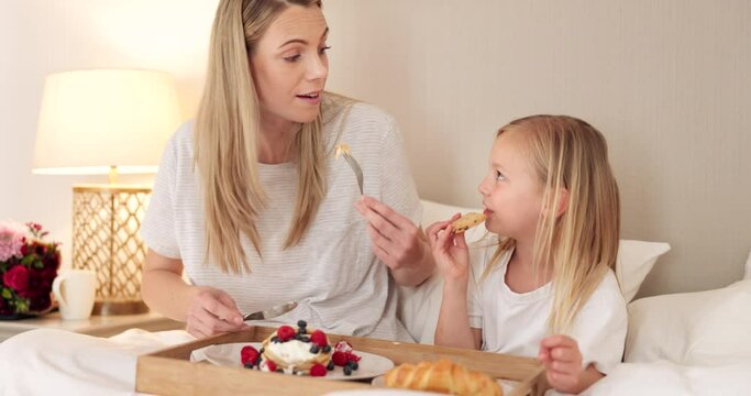 Mother, child and breakfast in the bed of their house together in the morning. Girl relax, calm and in peace while talking and eating food on mothers day with her mom in the bedroom of their home
