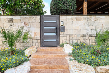 View of fence with metal door, intercom and mailbox