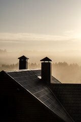 the roof of the house against the backdrop of a sunny foggy dawn