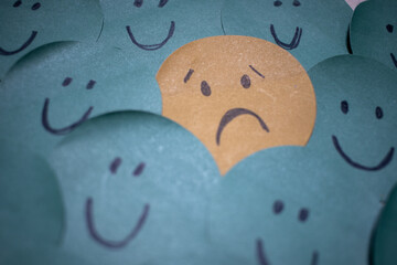 a sad face around happy faces - paper drawing