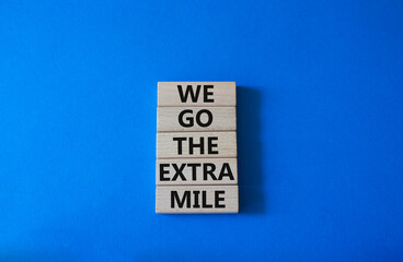 We go the extra mile symbol. Wooden blocks with words We go the extra mile. Beautiful blue background. Business and We go the extra mile concept. Copy space.