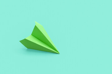 Green paper plane on color background
