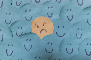 a sad face around happy faces - paper drawing