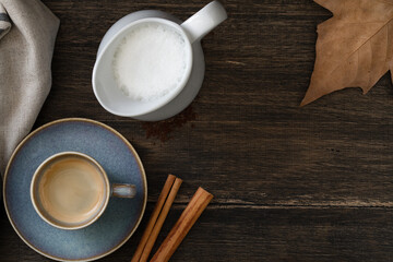 Blue coffee cup with milk jug. Cinnamon and autumn leaf.