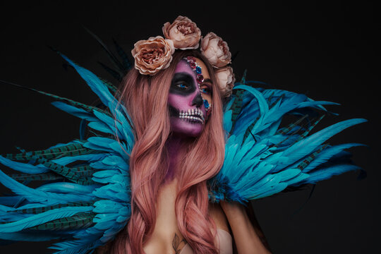 Shot of tattooed woman with muertos make up and blue wings.