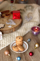 Various Christmas decorations, cup of tea or coffee, sweets, small presents, knitted blanket and candles. Selective focus.