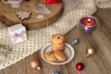 Various Christmas decorations, cup of tea or coffee, sweets, small presents, knitted blanket and candles. Selective focus.