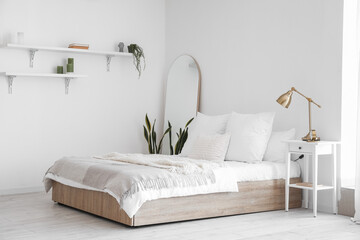 Interior of light bedroom with big bed, shelves and mirror