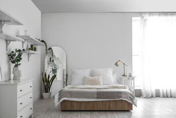 Interior of light bedroom with big bed, table and mirror