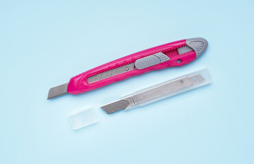 Pink utility knife with blades on blue background