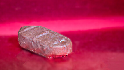 Naklejka premium Chocolate candy on a red metallic background