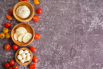 Composition with bowls of tasty mozzarella cheese and tomatoes on grunge background