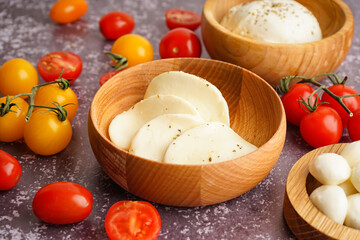 Bowls of delicious mozzarella cheese and tomatoes on grunge background, closeup
