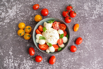 Bowl of delicious mozzarella cheese with tomatoes on grunge background