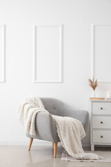 Grey armchair with plaid in interior of light living room