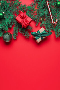 Composition with fir branches, Christmas gifts and decorations on red background