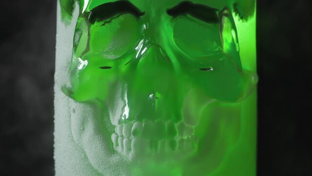 Bottle of Poison in Hoarfrost. A glass vessel with a bright, rich emerald-green content in the form of a glass skull, cooled by liquid evaporating nitrogen