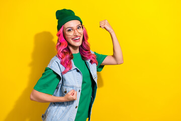 Portrait of lucky champion adorable girl curly hairdo wear green t-shirt raise fists scream yes isolated on yellow color background