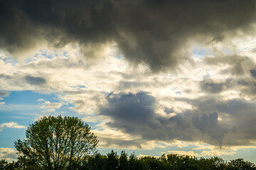 Ominous dark clouds in blue sky over forest