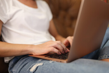 Naklejka premium Woman typing on modern laptop with sticker on cover