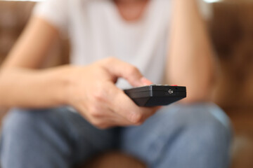 Female hand holding tv remote control and surfing programs on television