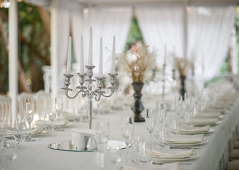 Soft-focus chandelier on white tablecloth. White curtains background.