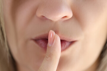 Young woman showing shh gesture or to keep silent sign