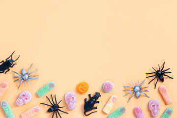 Halloween sweet background frame with scary pumpkin cookies, candy and Halloween decor on orange table