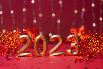 Golden numbers of year 2023. Happy New Year greeting card. Glowing festive garland with bokeh on red background.