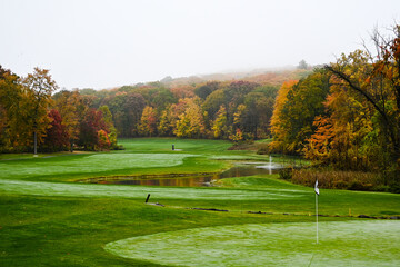 Fototapeta na wymiar A beautiful foggy fall day on the golf course during peak foliage season.