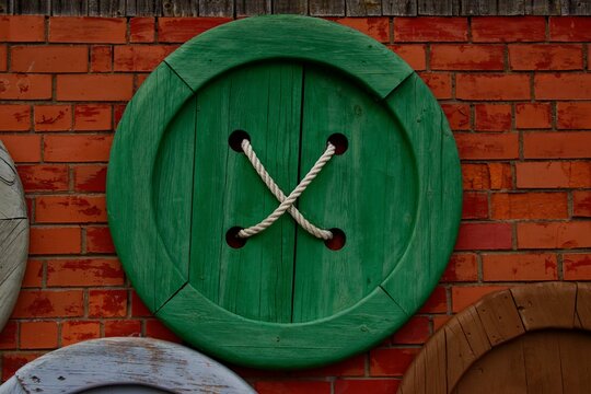 Green wooden button on the brick wall Talsi, Latvia