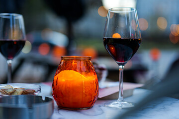 Glass of red wine and orange candle on table in brasserie