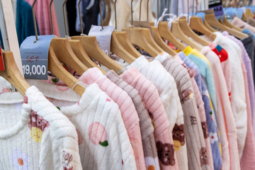 A shopping rank filled with clothes, pajamas and robes. Bunch of clothes of different colors for sale. Cheep clothing and fast fashion theme