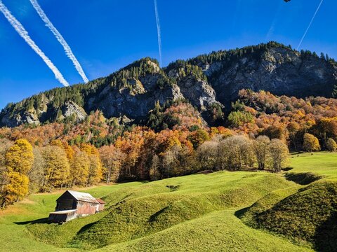 hiking in the beautiful Weisstannen valley in the canton of St. Gallen. Fall colors in the woods. Alp hut with a view of the mountains. High quality photo