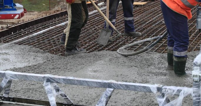 Concrete concrete slab. Working concrete foundation, rebar, pouring cement mortar on a reinforcing mesh or cage from a concrete mixer. Builders build hangar bridge, house