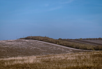 country gravel Dirt  curved road  in distance autumn blue sky field Moldova dry grass hill