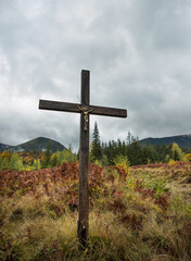 Fototapeta na wymiar Christian cross in the mountains among bright autumn vegetation.