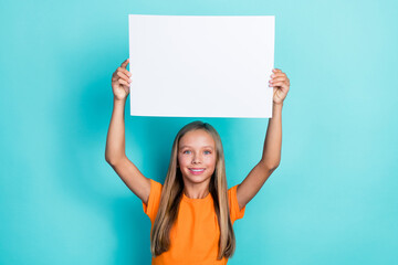 Photo of cute little schoolgirl kid blonde hair hold big paper white banner positive smiling enjoy...