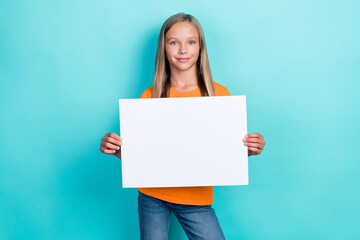 Photo of positive schoolkid girl hold white paper placard positive smiling recommendation offer...
