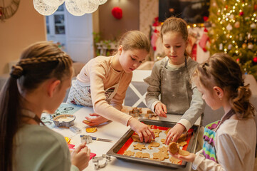 Girls have fun and joyfully prepare Christmas cookies at home in the kitchen