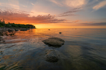 Fototapeta na wymiar Wonderful orange sunset on the rocky coast of the sea