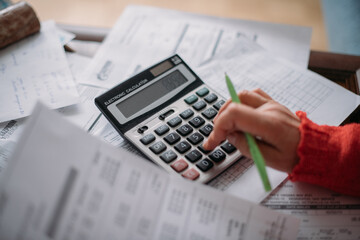 The hands of an elderly woman with a calculator and a lot of utility bills. Pensioner and payment of utilities for heating