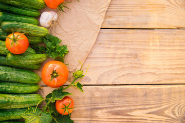 Fresh vegetables on a wooden background. Empty space for the text. Cucumbers, tomatoes, garlic, dill. Top view.