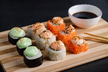 Set of sushi rolls on bamboo serving tray. Uramaki roll, chopsticks and soy sauce.