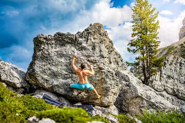 Naklejka na ściany i meble Sporty shirtless man climbs on boulder problem in the afternoon. Falzarego pass, Dolomites, South Tirol, Italy, Europe.