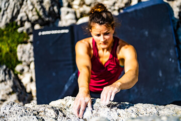 Sporty woman climbs on boulder problem in the afternoon. Falzarego pass, Dolomites, South Tirol,...