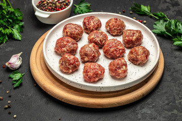 Fresh raw beef meatballs with spices on a cutting board on a dark background, banner, menu, recipe place for text, top view